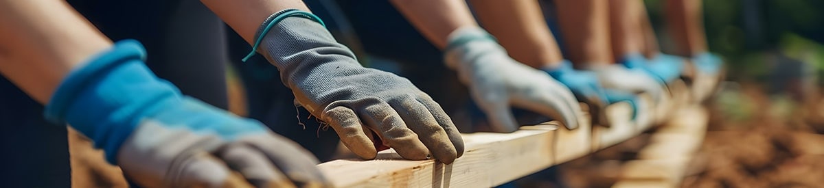 屋外で手袋を着用し、木材を扱う作業をする人々